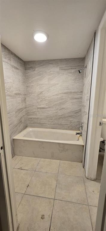 A bathroom features a tiled bathtub surround and light-colored floor tiles — 21440 MIDWAY BOULEVARD, PORT CHARLOTTE, FL