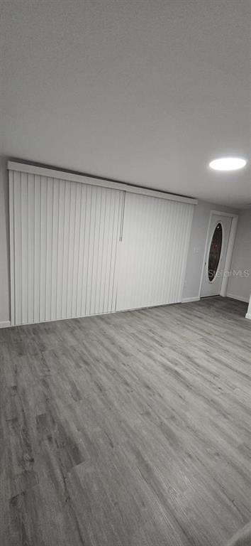 A room with gray wood-look flooring, white vertical blinds, and a door with an oval window — 21440 MIDWAY BOULEVARD, PORT CHARLOTTE, FL