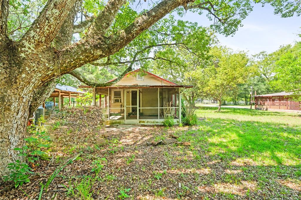 A small, weathered house with a screened-in porch sits under a large tree — 140 W PONKAN ROAD, APOPKA, FL