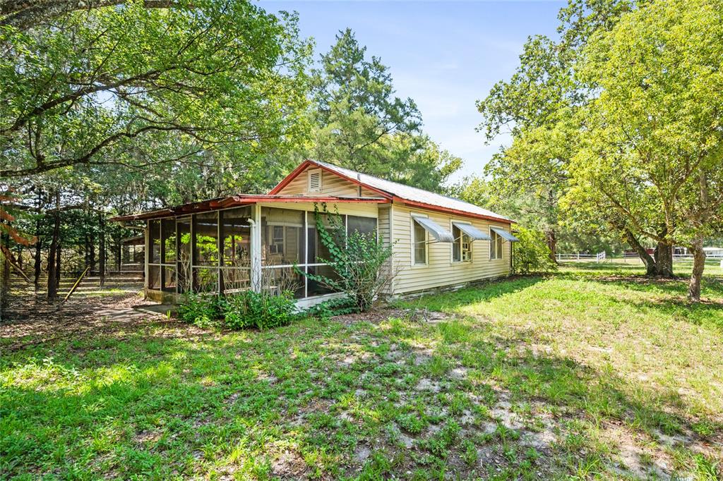 A single-story house with light-colored siding, a metal roof, and a screened-in front porch — 140 W PONKAN ROAD, APOPKA, FL