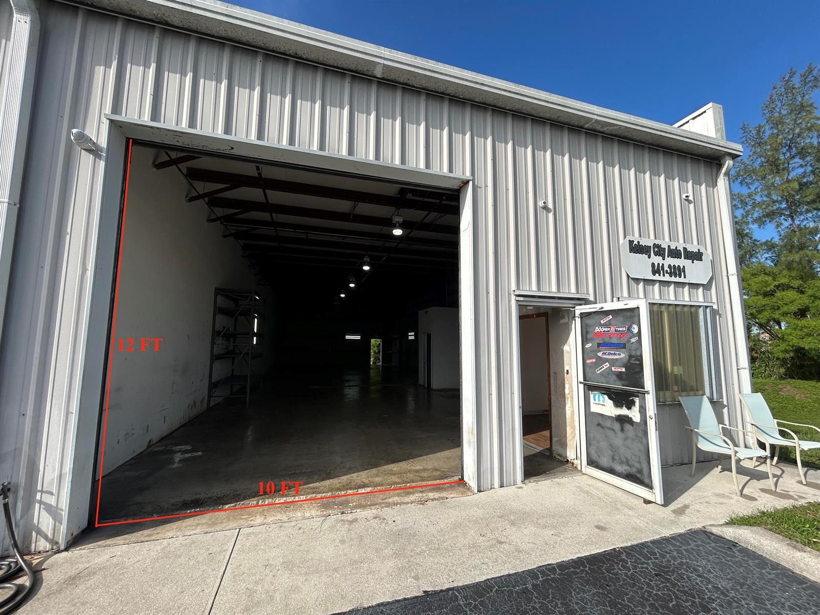 The exterior of a metal-sided commercial building features a large open bay door and entrance — 806 Old Dixie Highway # 1, Lake Park FL 33403, LAKE PARK, FL