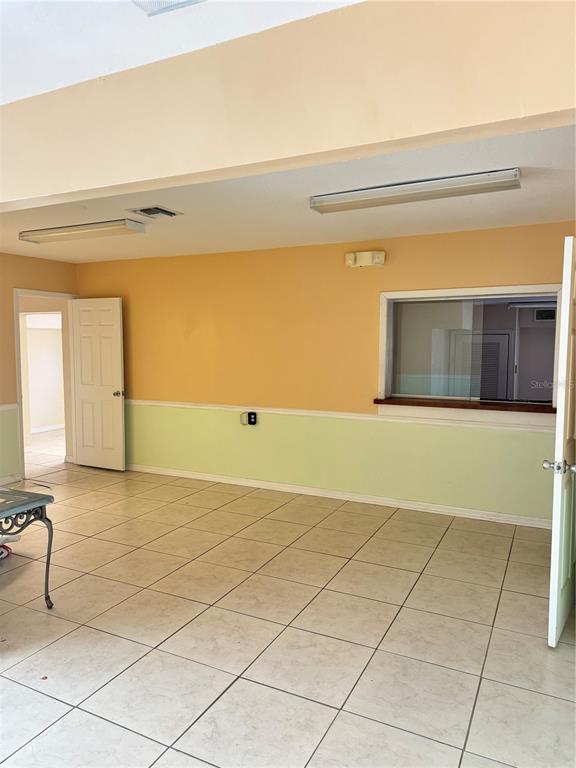 An interior room features light-colored tile flooring, two-toned walls, and a service window — 706 N 7TH STREET, FORT PIERCE, FL