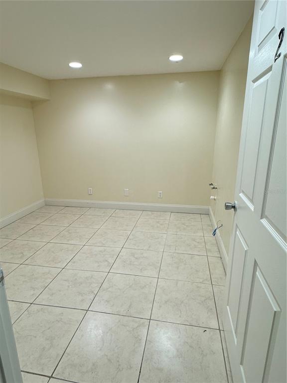An empty room with light-colored tile flooring, beige walls, and recessed ceiling lighting — 706 N 7TH STREET, FORT PIERCE, FL