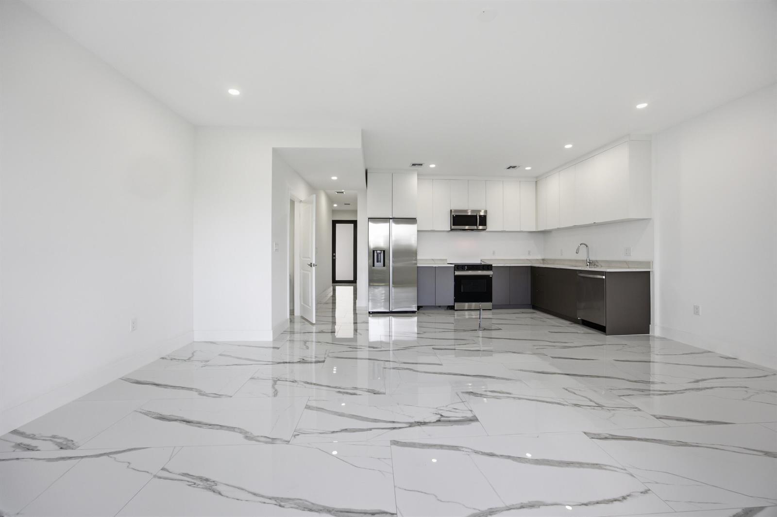 A modern kitchen with white upper cabinets, dark lower cabinets, and white marble-patterned tile flooring — 1544 NW 1st Avenue, Pompano Beach FL 33060, POMPANO BEACH, FL