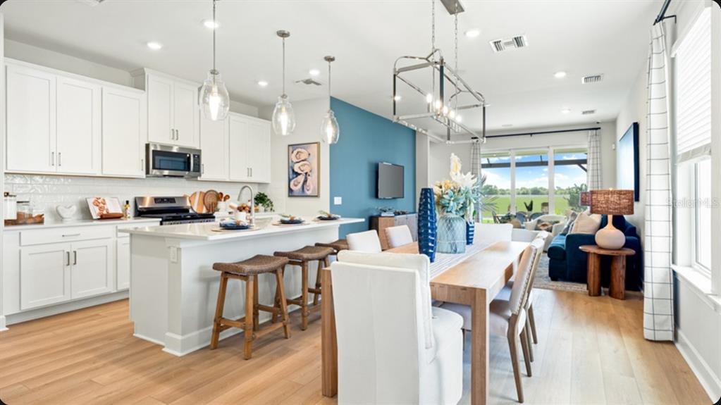 An open-concept kitchen and dining area features white cabinetry, a kitchen island, and blue accents — 4457 OCHOS RIOS PLACE, KISSIMMEE, FL