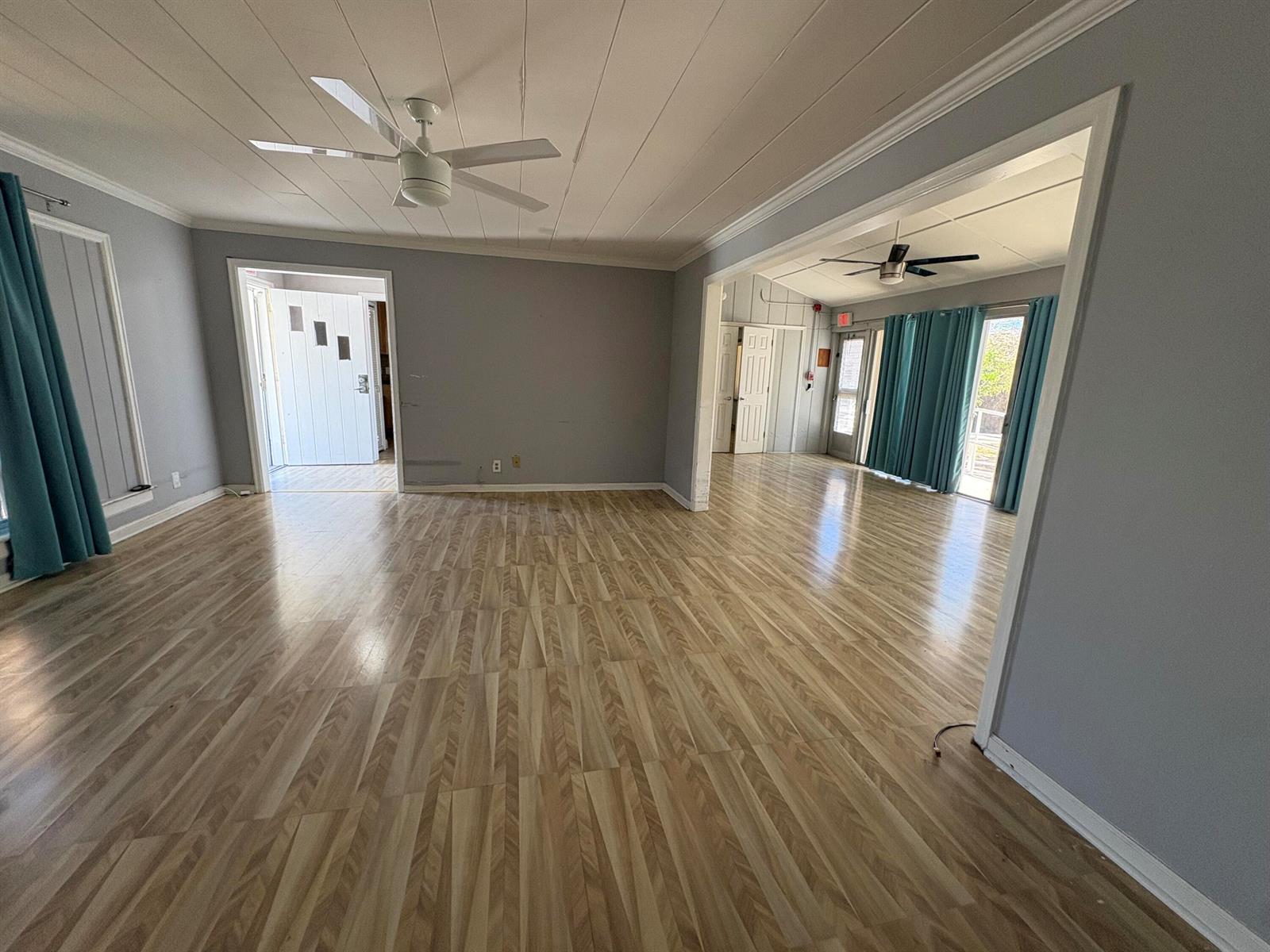 An empty room with light wood-look flooring, gray walls, and two ceiling fans — 202 Palm Court, Delray Beach FL 33444, DELRAY BEACH, FL