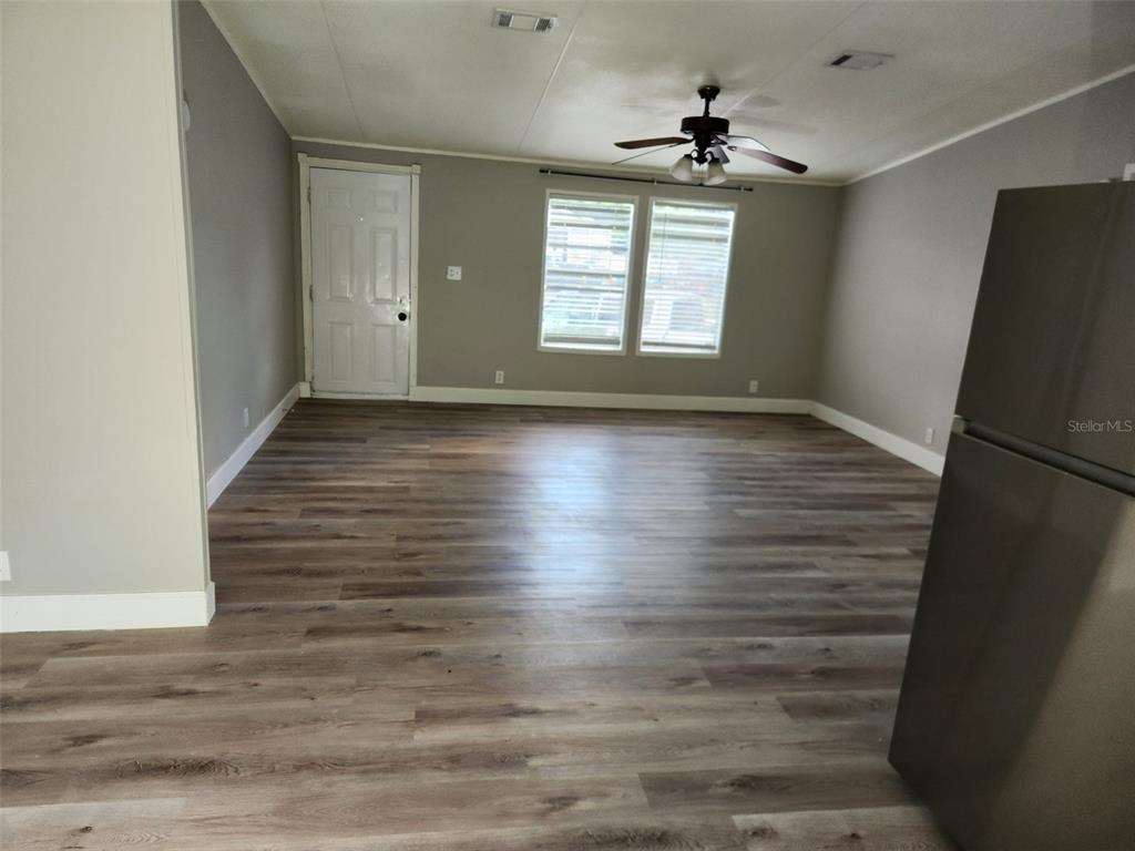 A living area features gray walls, wood-look flooring, a ceiling fan, and a white door — 9514 11TH AVENUE, ORLANDO, FL