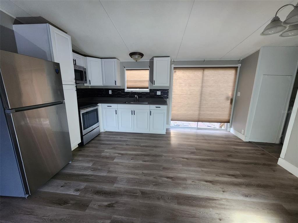 A kitchen with white cabinets, stainless steel appliances, and wood-look flooring — 9514 11TH AVENUE, ORLANDO, FL