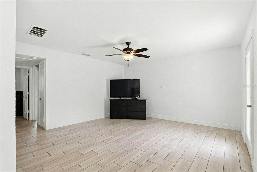 A living room with white walls, light wood-look tile flooring, and a ceiling fan — 2521 W CREST AVENUE, TAMPA, FL