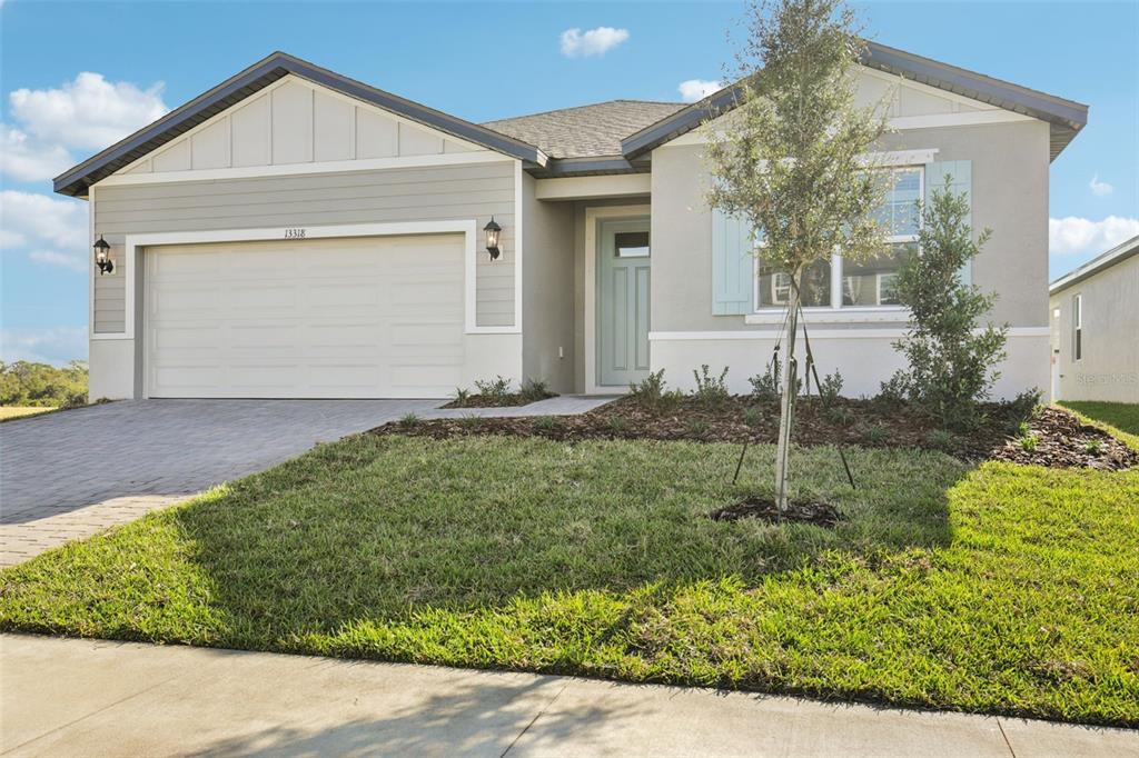 A single-story suburban house with a two-car garage, light gray siding, and a paved driveway — 13318 SHELLMORE AVENUE, PALMETTO, FL