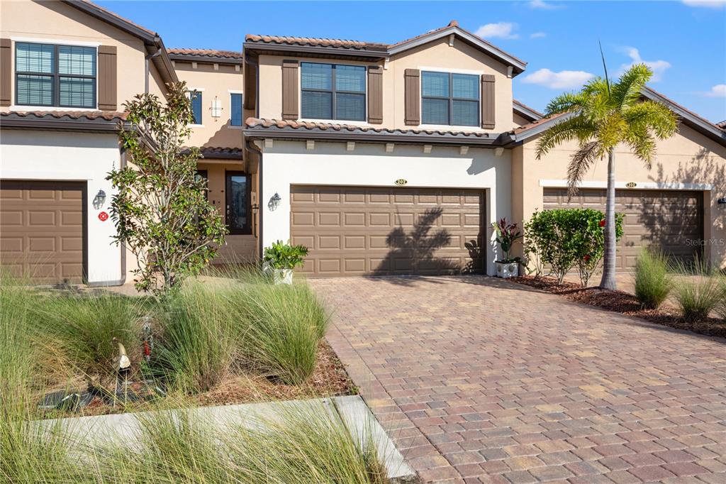 A two-story townhouse exterior features a paved driveway, a double garage, and a palm tree — 12460 GHIBERTI CIRCLE UNIT 202, VENICE, FL