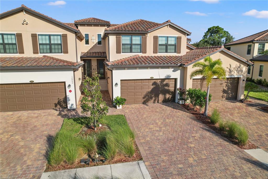 A multi-unit residential building features stucco walls, tile roofs, and paved driveways with garages — 12460 GHIBERTI CIRCLE UNIT 202, VENICE, FL