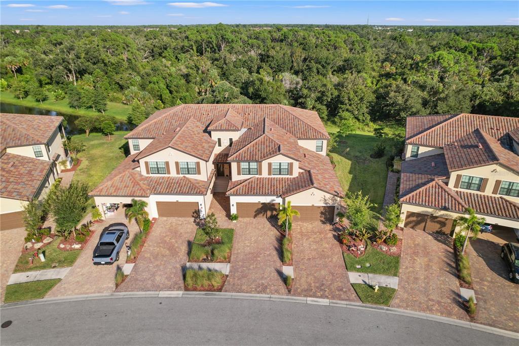 An aerial view shows a multi-unit residential building with tiled roofs and paved driveways — 12460 GHIBERTI CIRCLE UNIT 202, VENICE, FL