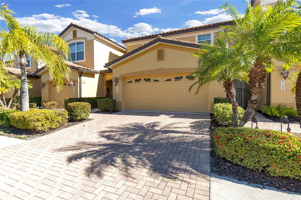 A two-story suburban house with a paved driveway, a two-car garage, and palm trees — 8141 MIRAMAR WAY UNIT 8141, LAKEWOOD RANCH, FL