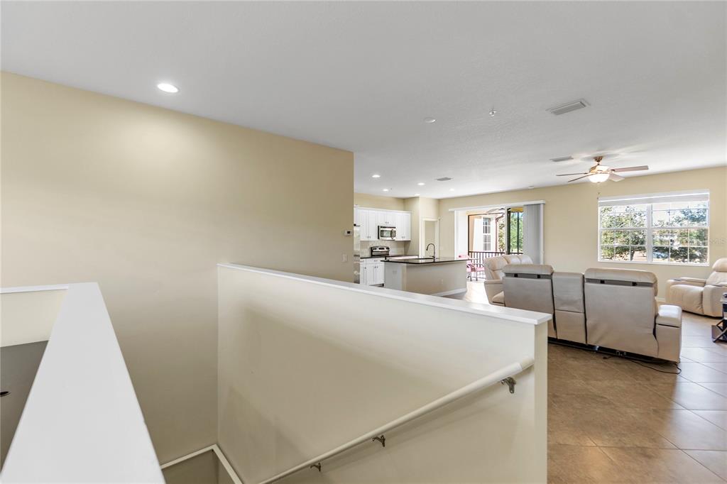 An elevated view overlooks an open-concept living room and kitchen with light-colored tile flooring — 8141 MIRAMAR WAY UNIT 8141, LAKEWOOD RANCH, FL