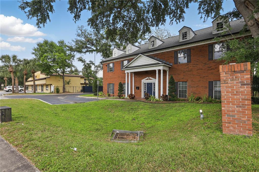 A two-story brick building with a columned entrance and dormer windows sits on a lawn — 5639 HANSEL AVENUE, ORLANDO, FL