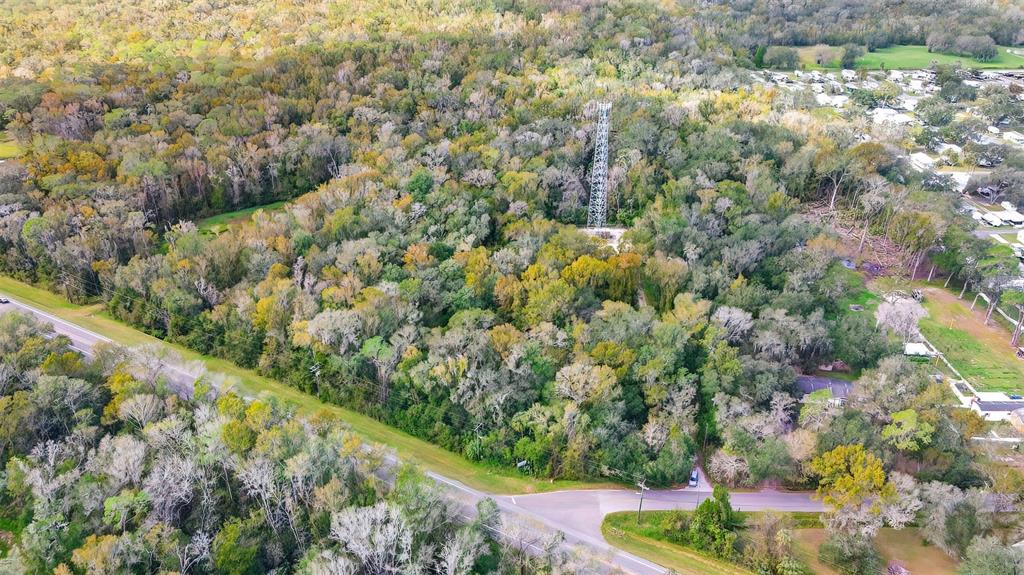 An aerial view shows a tall communication tower situated in a dense, wooded forest area — 14902 DEAD RIVER ROAD, THONOTOSASSA, FL