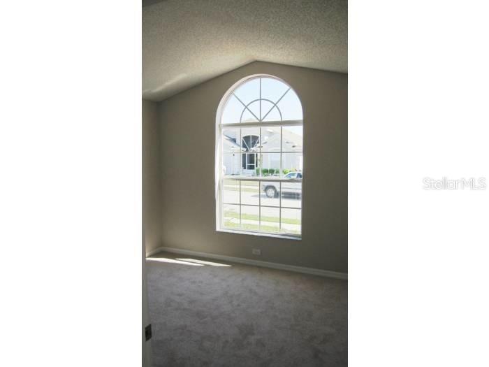 A carpeted room features a large arched window with a view of the street — 558 BRAYTON LANE, DAVENPORT, FL