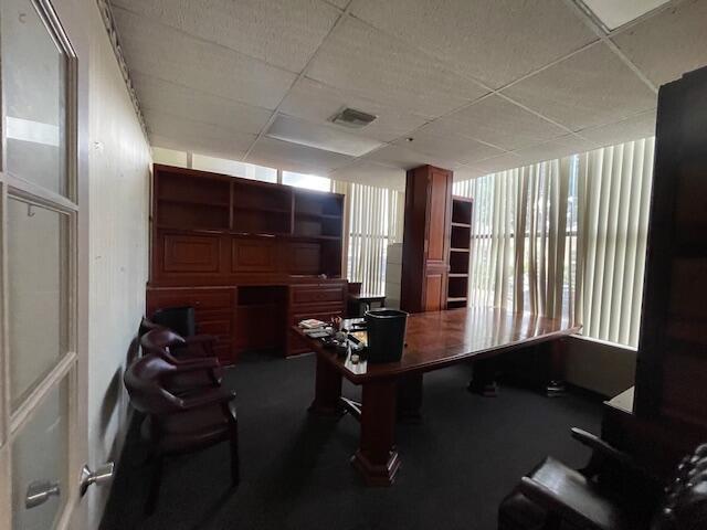 An office features a large wooden desk, matching wall shelving, dark chairs, and vertical blinds — 631 Us-1 # 101, North Palm Beach FL 33408, NORTH PALM BEACH, FL