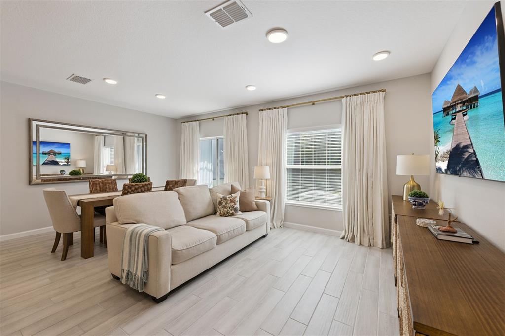 A living room features a beige sofa, dining area, large wall mirror, and light wood flooring — 3129 RIVERBOAT WAY, OVIEDO, FL
