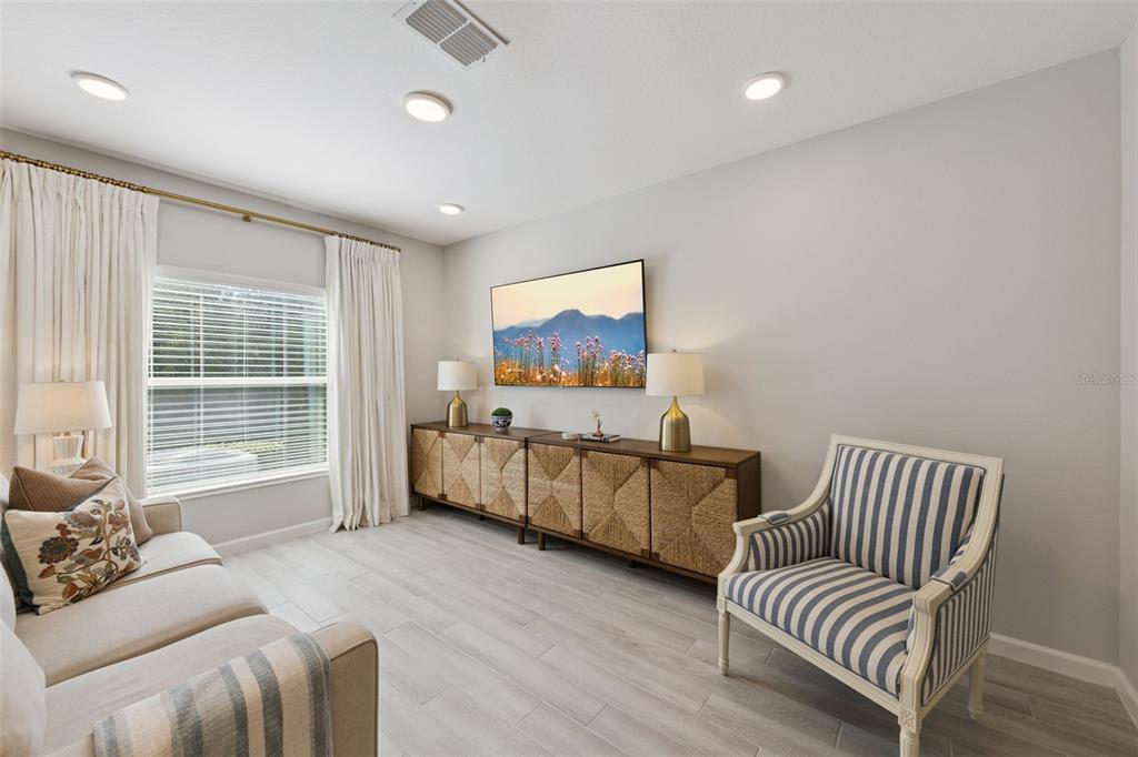 A living room features a sofa, a striped armchair, and a long wooden media console — 3129 RIVERBOAT WAY, OVIEDO, FL
