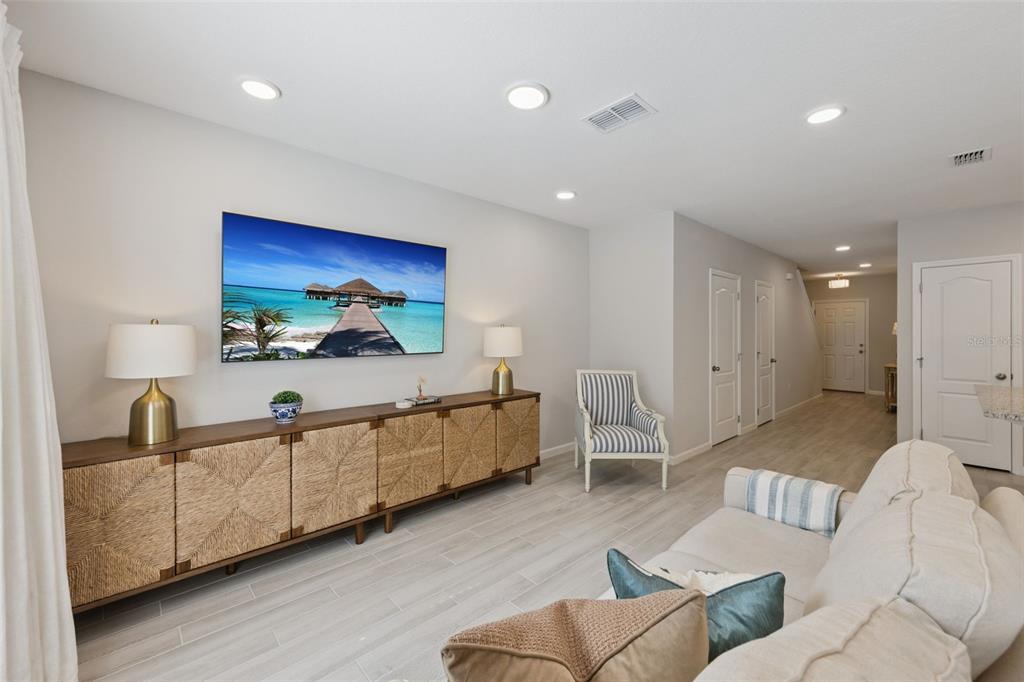 A living room features a wall-mounted television, a long woven console, and light wood flooring — 3129 RIVERBOAT WAY, OVIEDO, FL