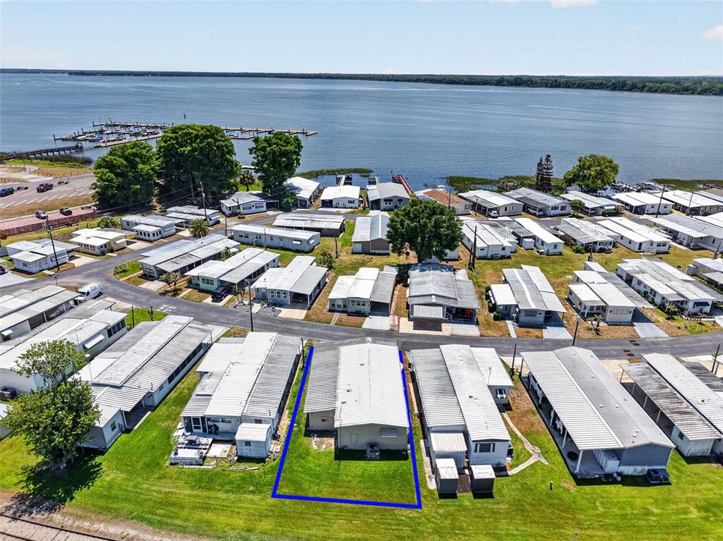 An aerial view shows a mobile home highlighted in blue within a lakeside community — 488 MARINA LANE, TAVARES, FL