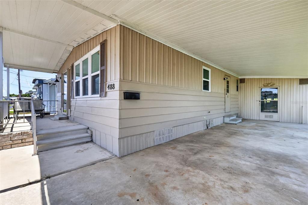 The exterior of a manufactured home features beige siding, a carport, and a concrete patio — 488 MARINA LANE, TAVARES, FL