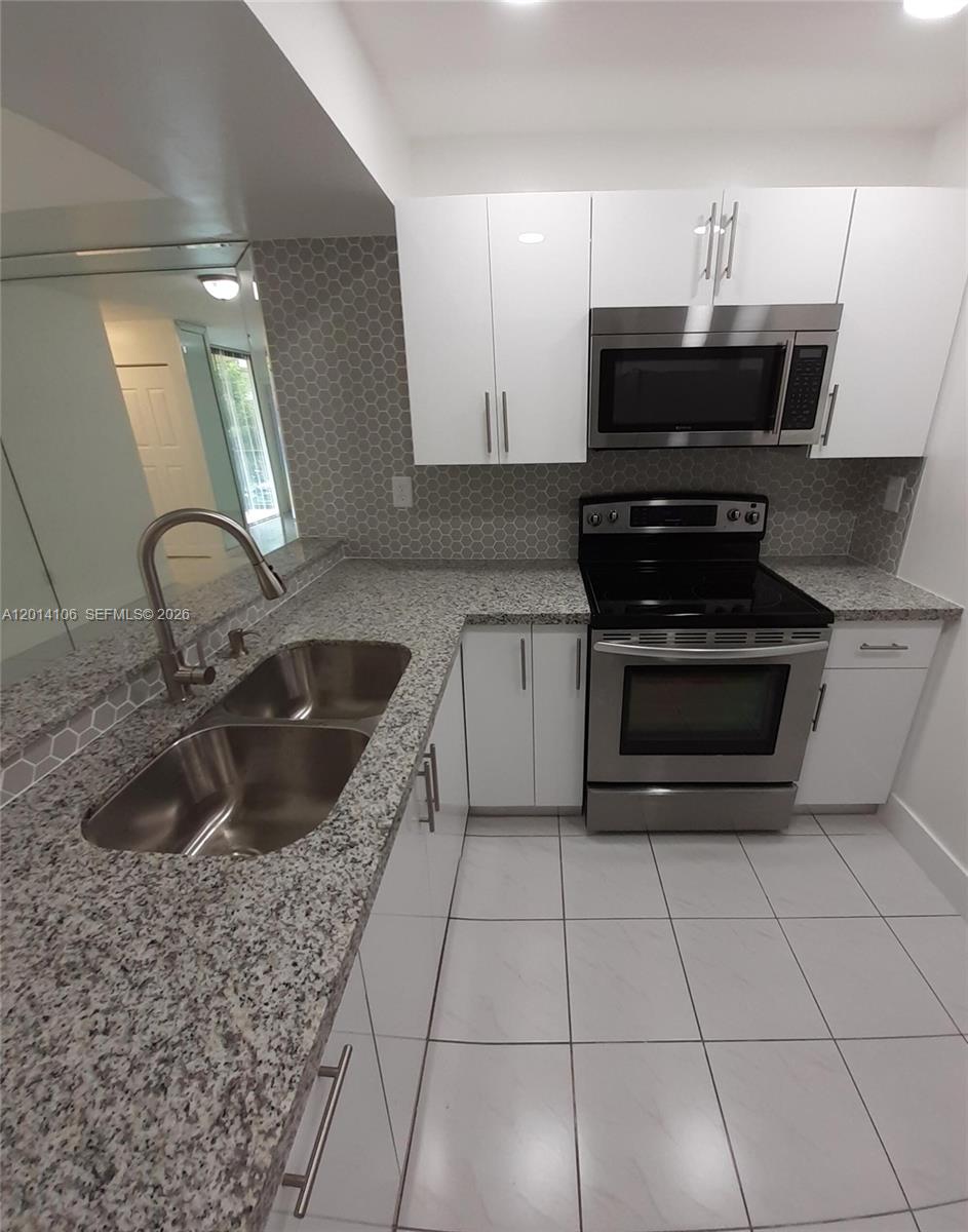 A kitchen features white cabinets, granite countertops, stainless steel appliances, and a gray hexagonal backsplash — 11800 SW 18th St # 4, Miami FL 33175, MIAMI, FL