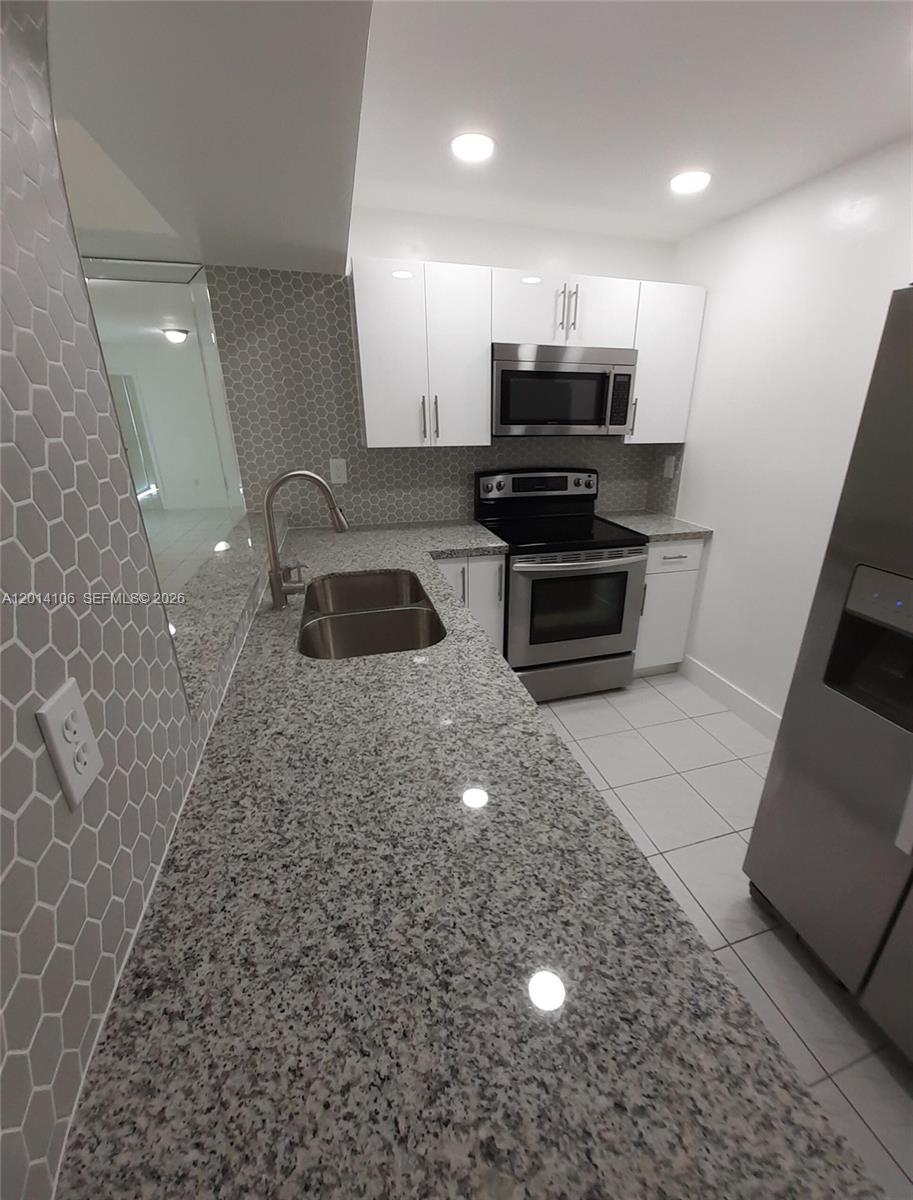 A kitchen features white cabinets, granite countertops, stainless steel appliances, and a gray hexagonal backsplash — 11800 SW 18th St # 4, Miami FL 33175, MIAMI, FL