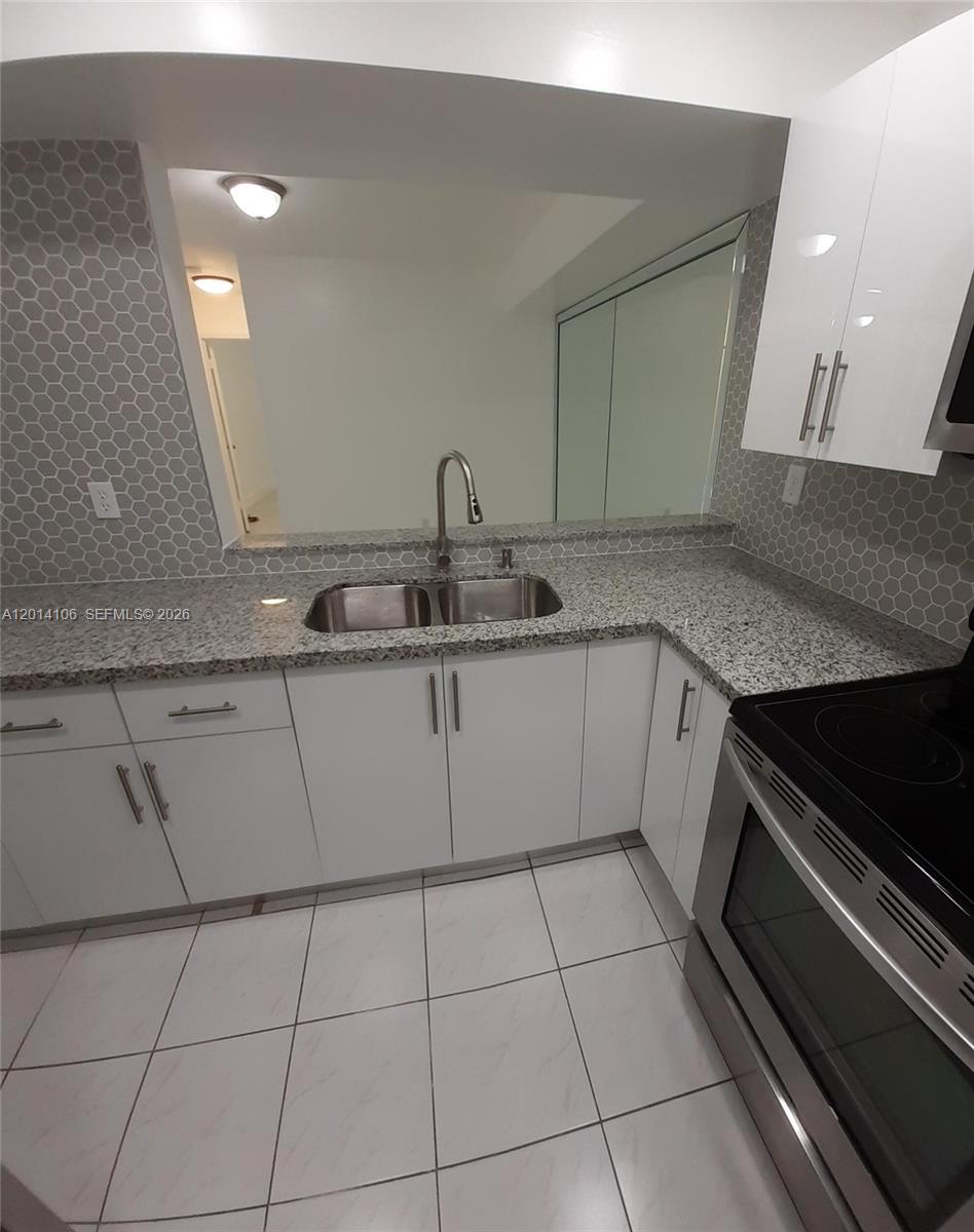 A kitchen features white cabinets, granite countertops, a stainless steel sink, and hexagonal tile backsplash — 11800 SW 18th St # 4, Miami FL 33175, MIAMI, FL