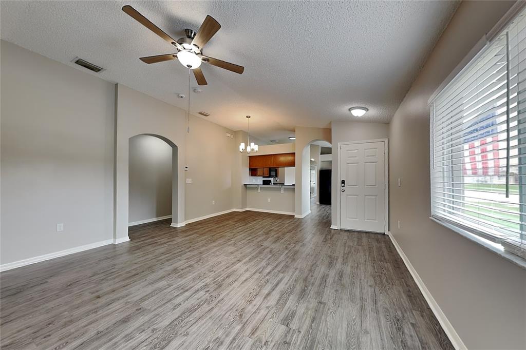 An open-concept living area features wood-look flooring, a ceiling fan, and an arched entryway — 11759 LYNMOOR DRIVE, RIVERVIEW, FL