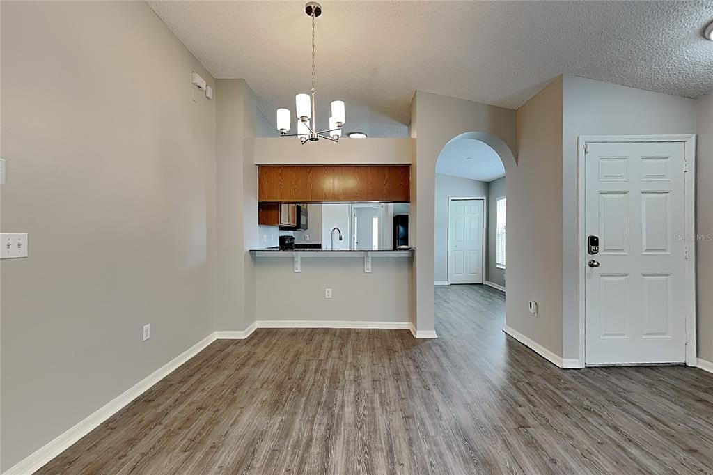 A dining area with wood-look flooring, a breakfast bar, and a chandelier — 11759 LYNMOOR DRIVE, RIVERVIEW, FL