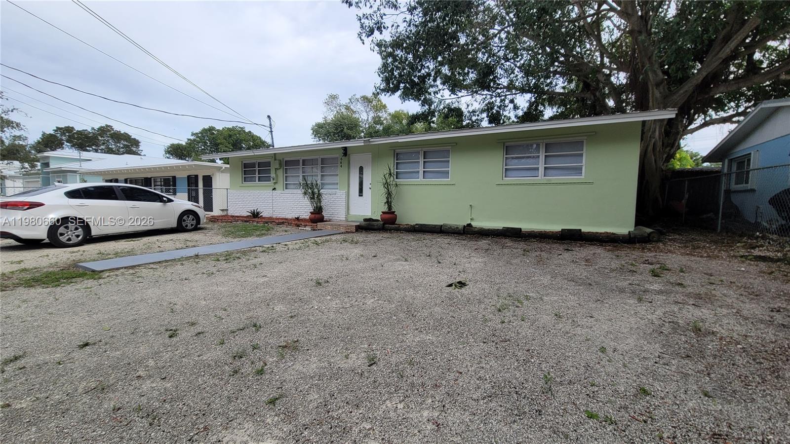 A single-story light green house with a gravel driveway and a large tree — 664 Colson Dr, Key Largo FL 33037, KEY LARGO, FL