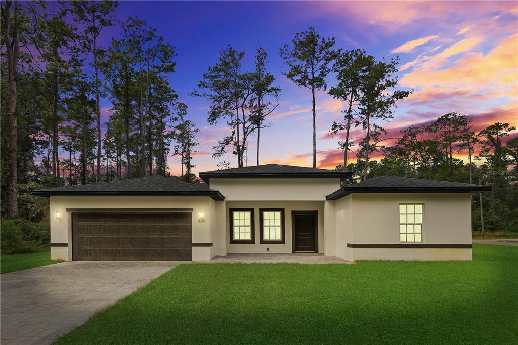 A single-story house with a two-car garage, white stucco exterior, and a paved driveway — 14519 SW 79TH AVE RD, OCALA, FL