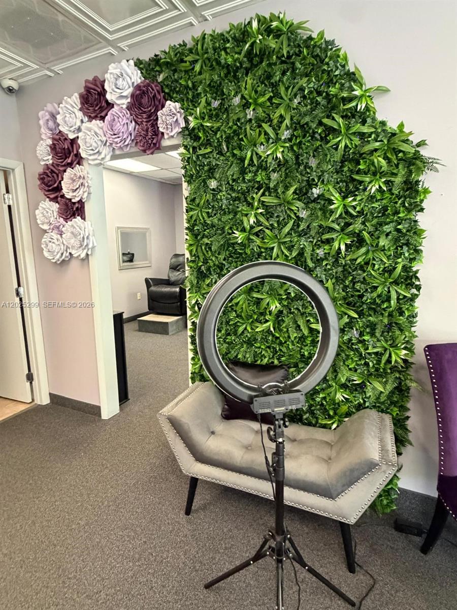 A grey tufted bench sits before a green wall adorned with large paper flowers — 2700-2750 N 29th Ave # 103, Hollywood FL 33020, HOLLYWOOD, FL