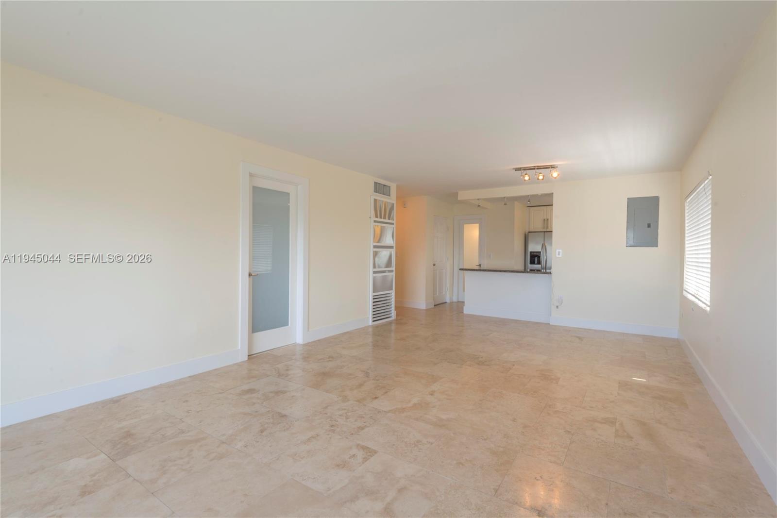 This living area features light-colored walls, large beige floor tiles, and an open kitchen — 1200 14th St # 5E, Miami Beach FL 33139, MIAMI BEACH, FL