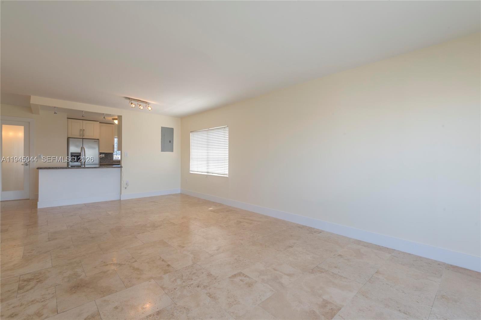 An open-concept living area features beige tile flooring, cream-colored walls, and a kitchen pass-through — 1200 14th St # 5E, Miami Beach FL 33139, MIAMI BEACH, FL
