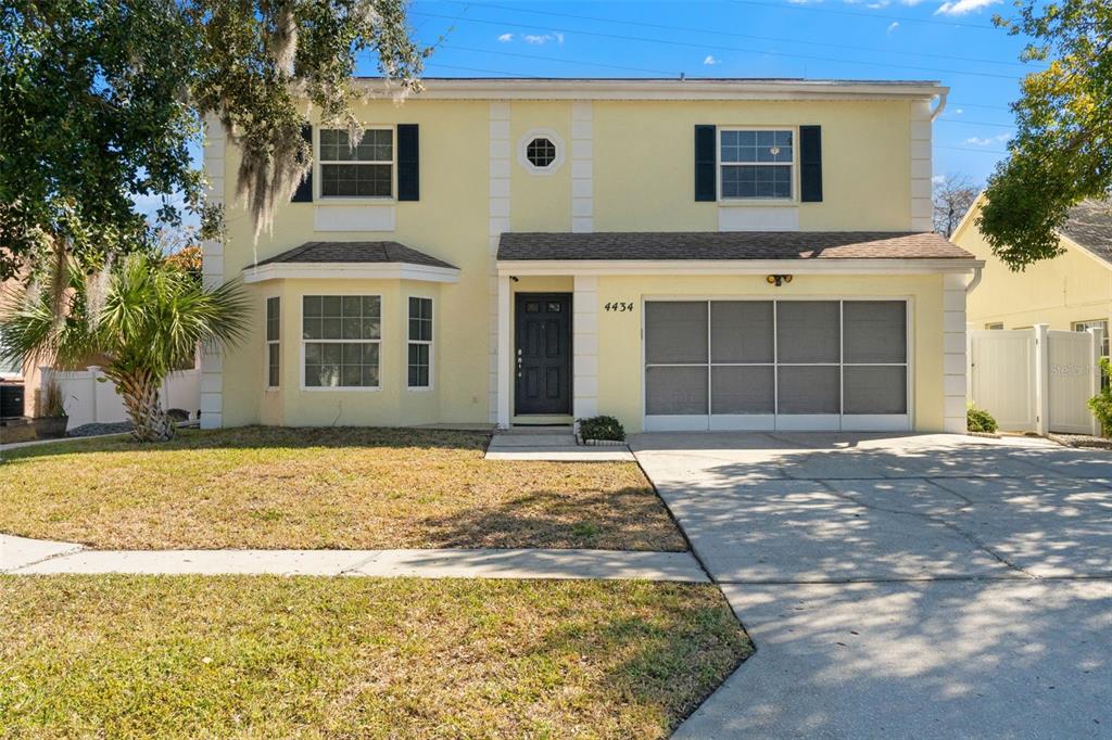 A two-story yellow house with a front-facing garage, a bay window, and a palm tree — 4434 NORTHAMPTON DRIVE, NEW PORT RICHEY, FL