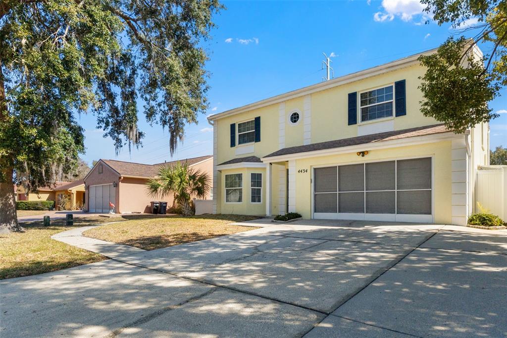 A two-story yellow house with a screened garage and a concrete driveway — 4434 NORTHAMPTON DRIVE, NEW PORT RICHEY, FL