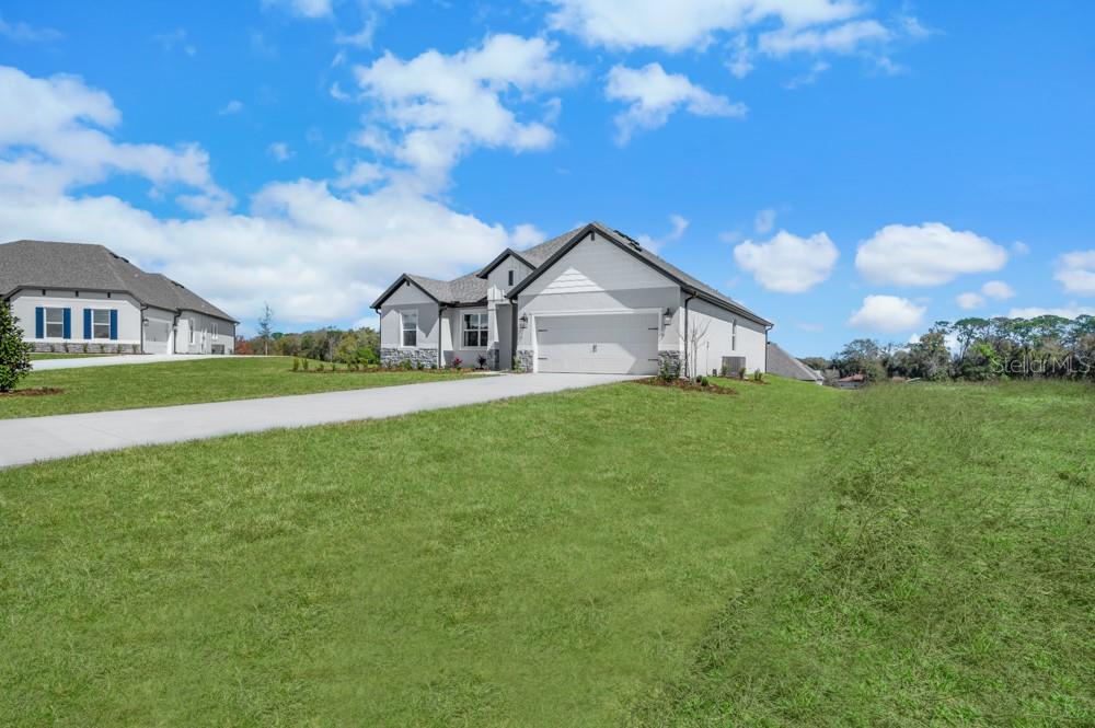 A single-story house with a white exterior, stone accents, and a two-car garage — 36794 SUNDOWNER TRAIL, FRUITLAND PARK, FL