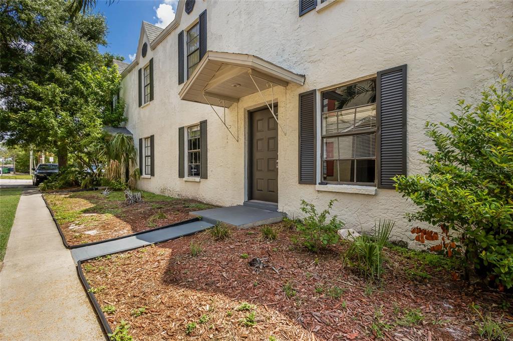 A two-story stucco building features a dark front door with a small metal awning — 3810 W CLEVELAND STREET, TAMPA, FL