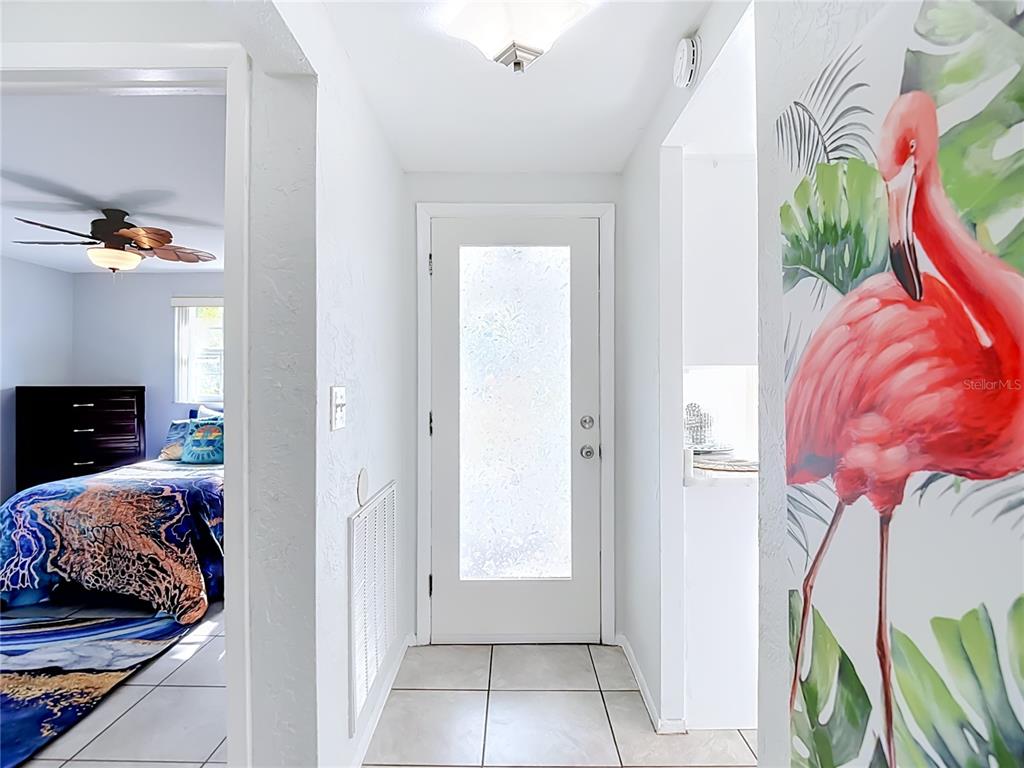 A tiled entryway features a white front door and a wall with flamingo wallpaper — 4227 TOUCHTON PLACE UNIT 4227, NEW PORT RICHEY, FL