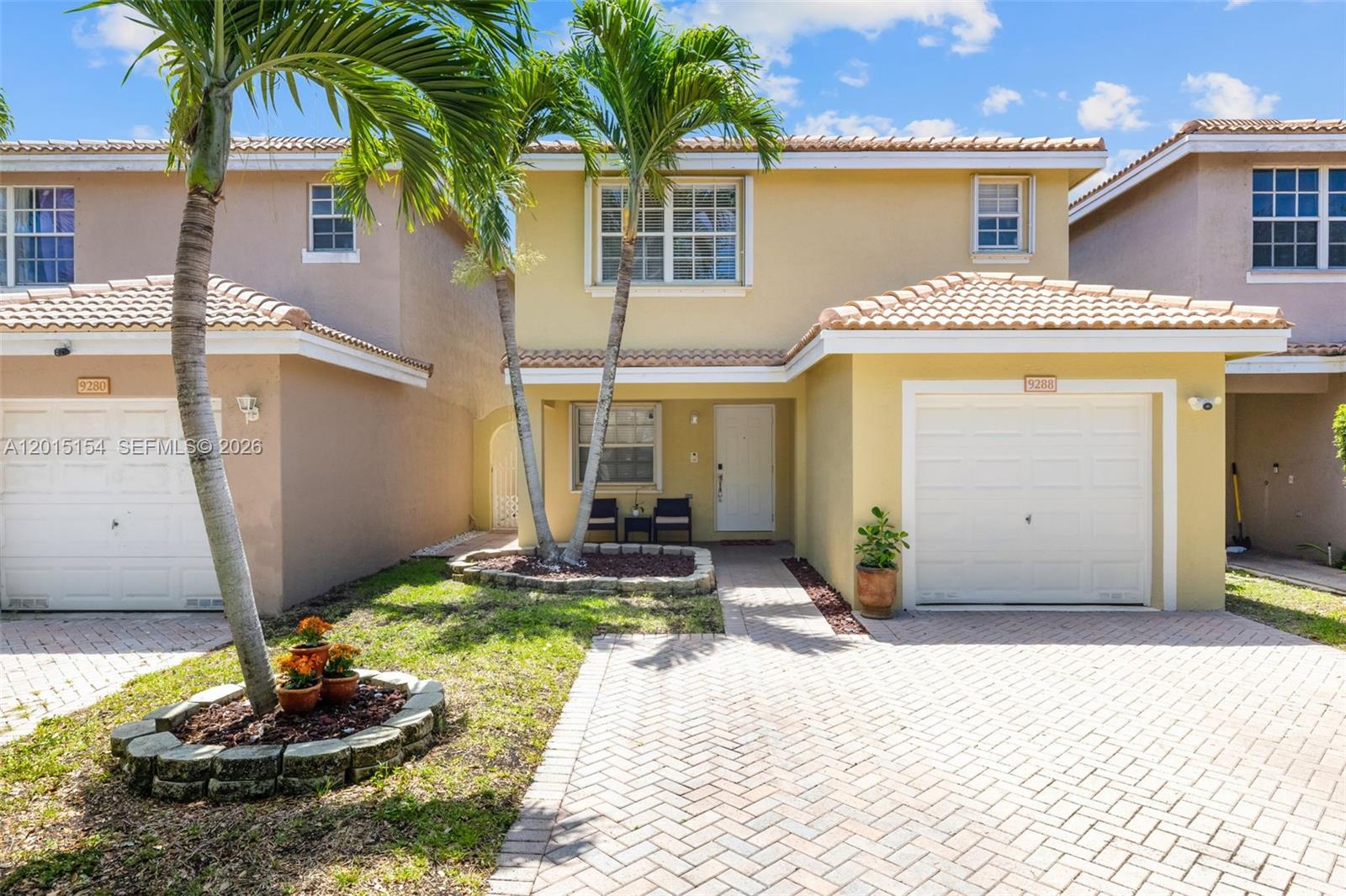 A two-story yellow house with a paved driveway, palm trees, and a single-car garage — 9288 NW 55th St, Sunrise FL 33351, SUNRISE, FL