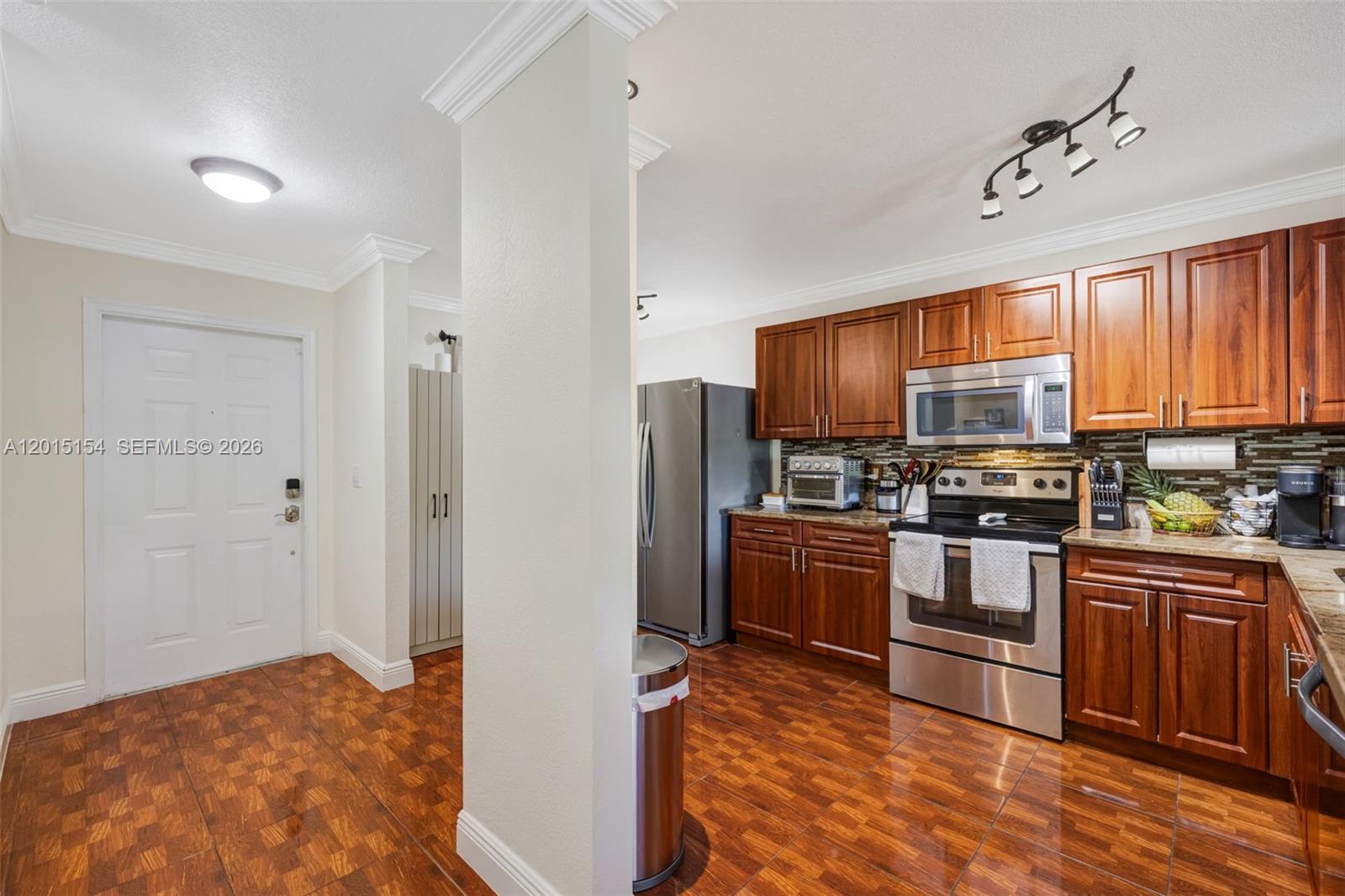 A kitchen features wood cabinets, stainless steel appliances, and brown tiled flooring — 9288 NW 55th St, Sunrise FL 33351, SUNRISE, FL