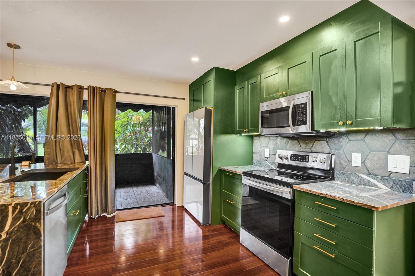 A kitchen features green cabinets, stainless steel appliances, and a sliding door to a patio — 3621 Lime Hill Rd # 202, Lauderhill FL 33319, LAUDERHILL, FL