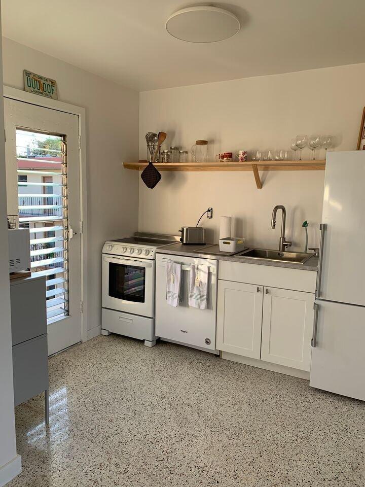 A small kitchen features white cabinets, stainless steel appliances, a wooden shelf, and terrazzo flooring — 649 SW 9th Street # 301, Miami FL 33130, MIAMI, FL