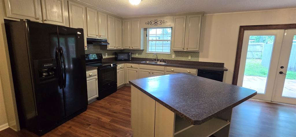 A kitchen features light-colored cabinets, dark countertops, a black refrigerator, and a center island — 5401 NW 63RD PLACE, OCALA, FL