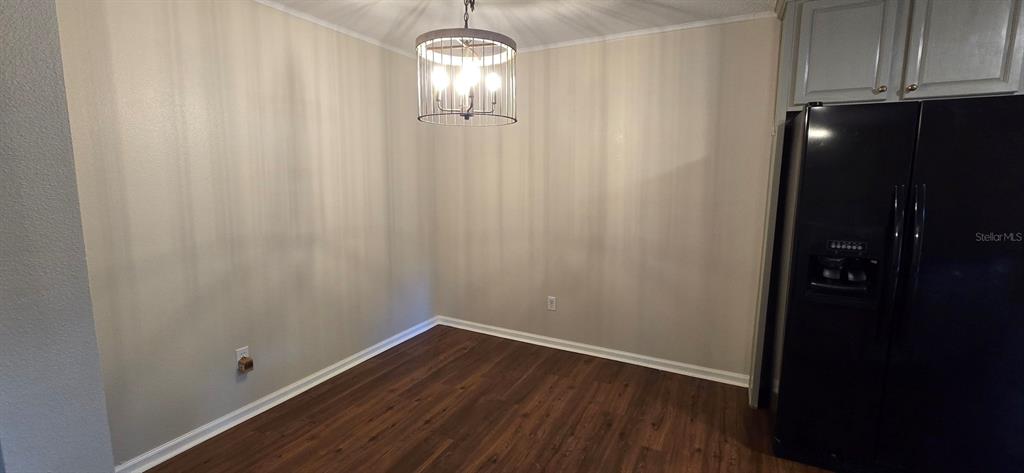 A dining area features wood-look flooring, a modern chandelier, and a black refrigerator — 5401 NW 63RD PLACE, OCALA, FL