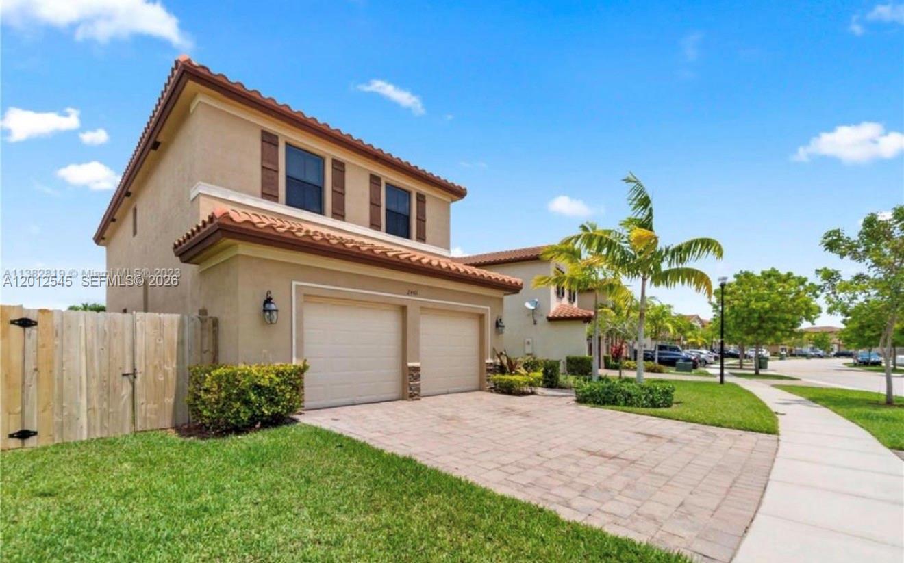 A two-story suburban house features a paved driveway, a two-car garage, and a tiled roof — 2401 NE 2nd Dr, Homestead FL 33033, HOMESTEAD, FL